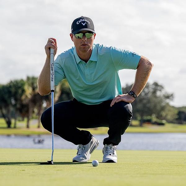 Golf green with a black and white checkered flag on a sunny day