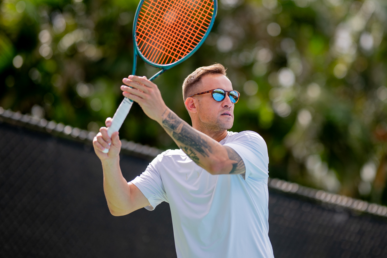 Male tennis player hitting a forehand in RIA Eyewear tennis sunglasses